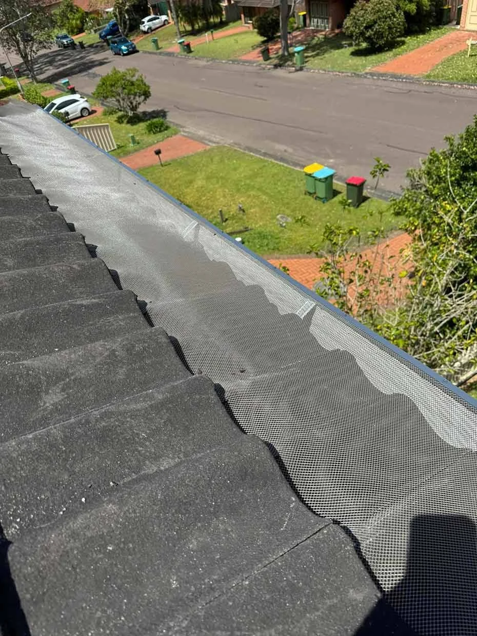 Black leaf guard mesh laid over the open top of a house gutter